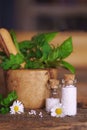 Medical glas vials on wooden table, filled with globulis. Decoratet with leaves and flowers.