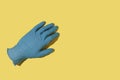 Medical glove without a hand inside on a yellow background.