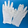 Two medical gloves of white color on a blue background.
