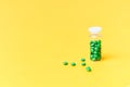 Medical green pills in a glass bottle on yellow background copyspace, health Royalty Free Stock Photo