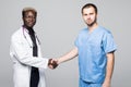 Medical handshake. Doctoral meeting. Two confident doctor standing on gray and shake their hands.