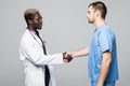 Medical handshake. Doctoral meeting. Two confident doctor and surgeon standing on gray and shake their hands.