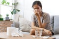 Sick Asian young woman sneeze at home on the sofa with a cold, she is  blowing her nose. Royalty Free Stock Photo