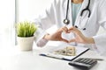 Medical and health insurance concept, Doctor doing hand heart shape gesture with money in hospital background.