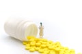 Medical and Healthcare Concept. Closeup doctor miniature figure people with file standing with yellow pills with bottle on white Royalty Free Stock Photo