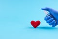 Medical heart treatment. person with blue latex gloves use sanitizer for heart symbol over blue background. copy space