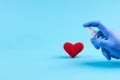 Medical heart treatment. person with blue latex gloves use sanitizer for heart symbol over blue background. copy space