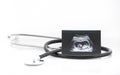 Medical images collage of ultrasound during woman pregnancy showing fetus in third month and stetoscope on white background
