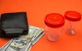 Medical insurance theme. Close-up of a wallet, 100 dollar bills, plastic containers for collecting analysis. Medical research expe Royalty Free Stock Photo