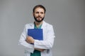 Medical Internship. Portrait Of Happy Male Doctor Student In Uniform Holding Clipboard In Hands And Posing Over Light Background Royalty Free Stock Photo