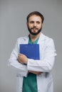 Medical Internship. Portrait Of Happy Male Doctor Student In Uniform Holding Clipboard In Hands And Posing Over Light Background Royalty Free Stock Photo