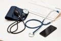 Medical items: blood pressure cuff, stethoscope, telephone keyboard on a wooden table. Online doctor Royalty Free Stock Photo