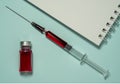 Medical jar with red liquid, glass syringe with red liquid and notepad Royalty Free Stock Photo