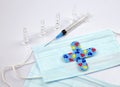 Medical kid`s adhesive in shape of cross on blue mask, syringe, ampules on white background. Selective focus