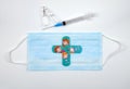 Medical kid`s adhesive in shape of cross on blue mask, syringe, ampules on white background. Selective focus