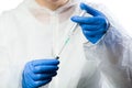 Medical lab technician inserting syringe needle into bottle ampoule