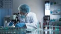 Medical lab worker examining laboratory glass with sample through microscope Royalty Free Stock Photo