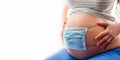 Medical mask on the belly of pregnant woman. Child protection. Concept of coronavirus, covid quarantine. Pregnant woman use face Royalty Free Stock Photo