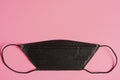 Medical mask black color to cover the mouth and nose for protection from bacteria on a pink background. space for text