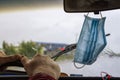 Medical mask on a car mirror close-up, against the background of a windshield cleaner in the rain Royalty Free Stock Photo