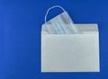 medical mask in an envelope on a blue background, isolates, Royalty Free Stock Photo