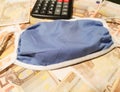 Medical mask on fifty euro banknotes and calculator