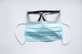 Medical mask and glasses lie on a white background, uniform Royalty Free Stock Photo