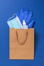 Medical mask, gloves and sanitizer in a paper bag on a blue background Royalty Free Stock Photo
