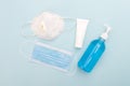 Medical mask and hand sanitizer gel on blue background