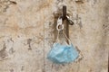 Medical mask and handcuffs hang on a stone wall on a hook