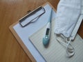 Medical mask KF94 with thermometers, notebooks and paper clipboards on the wooden floor