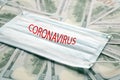 Medical mask laying on dollars, concept of increasing costs for protection of virus like the coronavirus or Covid19