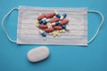 A medical mask and a lot of pills and pills on it fnd a soap on a blue background