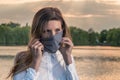 Medical mask protection against coronavirus and other viruses. Portrait of a woman against a lake at evening