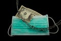 Medical mask separating a ripped dollar bill and barbed wire laying on top as concept of dividing a nation due to the coronavirus Royalty Free Stock Photo