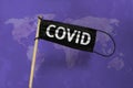 The medical mask Waving black flag on pole with text COVID. Black mask on violet the world map textured background. Black virus
