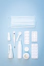 Medical mask, white thermometer, pills, vials with nasal spray and throat spray on a blue background Royalty Free Stock Photo