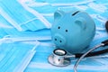 On medical masks lies a stethoscope and a piggy bank. Royalty Free Stock Photo