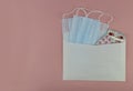 medical masks and tablets in an envelope on a pink background, isolates, Royalty Free Stock Photo