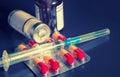 Medical objects on dark background - syringe, glass vials and pack of colorful polls copyspace