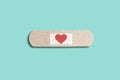 Medical patch with red heart on blue background. Abstract love concept, healing patch, broken love