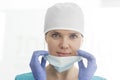 Closeup portrait of smiling doctor wearing surgical cap removing mask at clinic