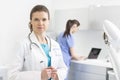 Portrait of smiling doctor standing against nurse using laptop in clinic Royalty Free Stock Photo