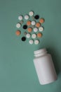 Medical pills of different colors and a white plastic bottle. Blue pastel background. Medicines. Close-up. Copy space. Royalty Free Stock Photo