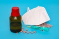 Medical pills are scattered on a blue background. Glass vial, syringe and face shield