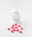 Medical pink pills and white bottle on white light background. Concept of healthcare and medicine. Royalty Free Stock Photo