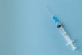 Medical plastic syringe with a needle filled with liquid on blue Royalty Free Stock Photo