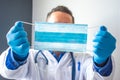 Medical professional, scientist or doctor holds medical mask in outstretched hands near front of camera close-up. Prevention of vi