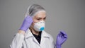 Medical professional woman is putting filtering half mask with exhalation valve on her face, protection