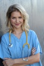 Medical professionals: Woman nurse smiling while working at hospital. Young beautiful blond caucasian female health care worker Royalty Free Stock Photo